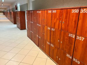 szafki szkolne w kolorze drewna ustawione pod ścianą na korytarzu szkolnym