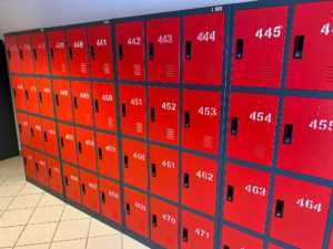 szafki szkolne w kolorze czerwonym ustawione pod ścianą na korytarzu szkolnym