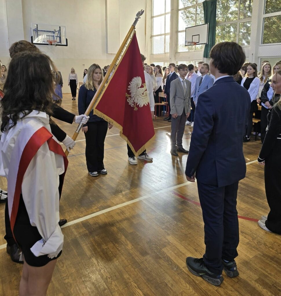 Na zdjęciu sztandar czwartego liceum oraz uczniowie, którzy ślubują w Dzień Edukacji Narodowej w tle uczniowie szkoły.