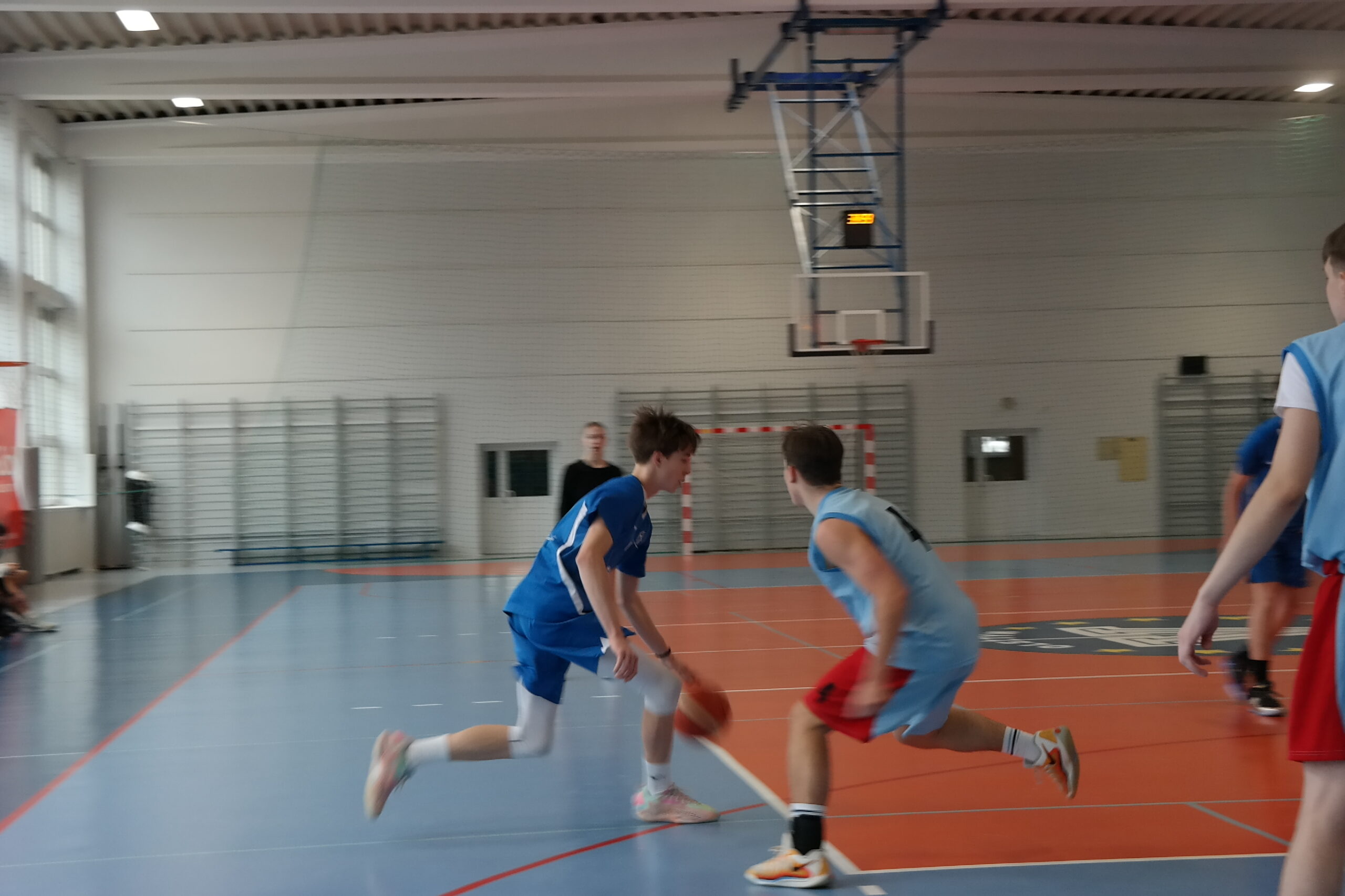 Dwóch zawodników walczy o piłkę podczas turnieju koszykówki.